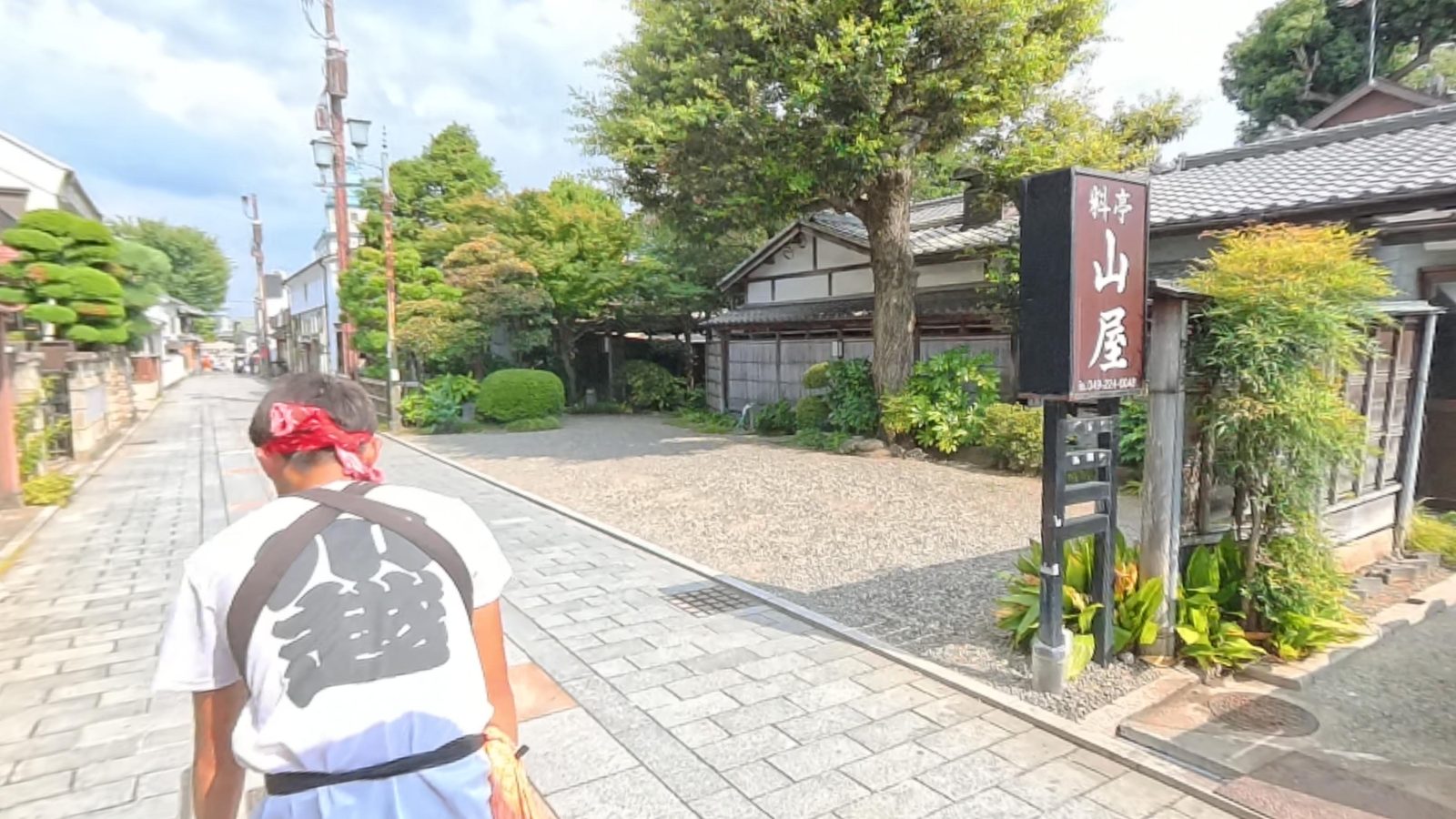 ทางเข้าร้านอาหารเรียวเตยามายะในคาวาโกเอะ มีป้ายไม้และต้นไม้เขียวครึ้ม